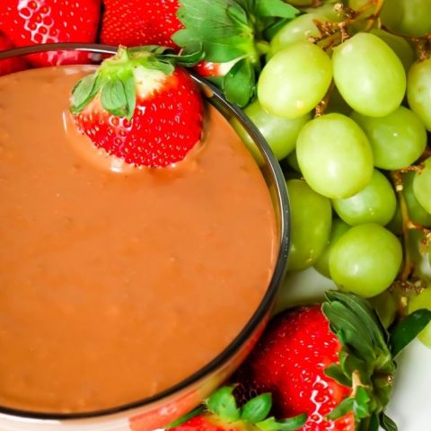 NUTELLA MARSHMALLOW DIP in a bowl surrounded by green grapes and red strawberries