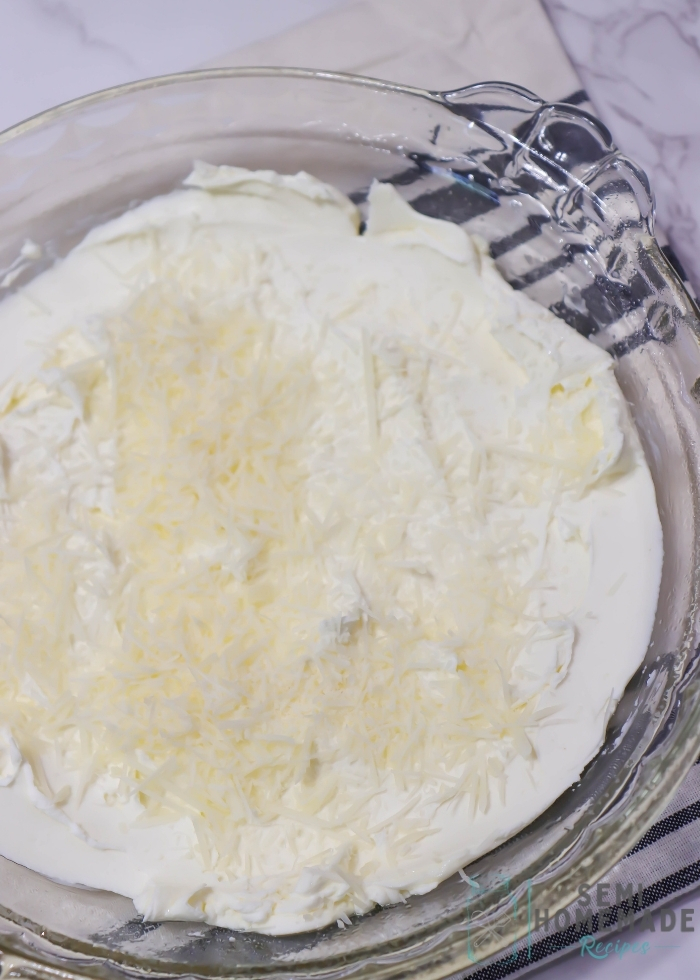 Cream cheese spread in a pie dish with parm cheese