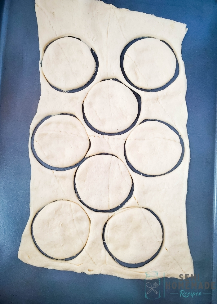 cutting circles of crescent dough on baking sheet
