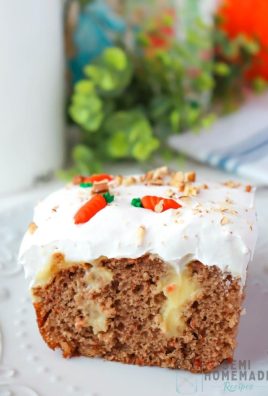 Slice of CARROT CAKE POKE CAKE on white plate with green in the background