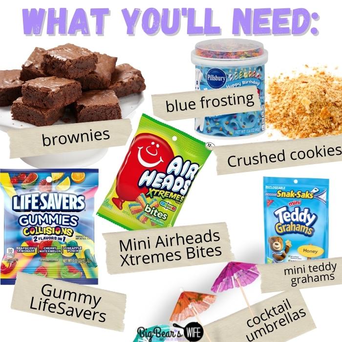 1 box brownie mix* 1/4 Cup Water 2/3 Cup Vegetable Oil 2 eggs 1 can blue colored vanilla frosting Crushed graham crackers or crushed vanilla wafers Mini Teddy Graham Crackers Gummy LifeSavers Mini Airheads Xtremes Bites Mini Toothpick Umbrellas