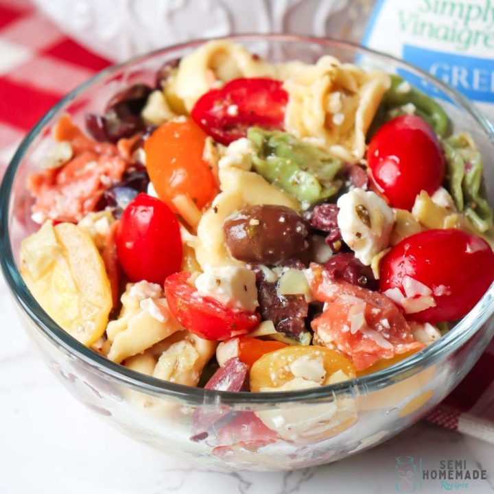 Greek Pasta salad is so easy to make and the perfect make ahead side dish! Cheese tortellini is tossed together with artichoke hearts, kalamata olives, garlic, tomatoes and feta before being mixed with Greek salad dressing for a tasty and simple recipe!