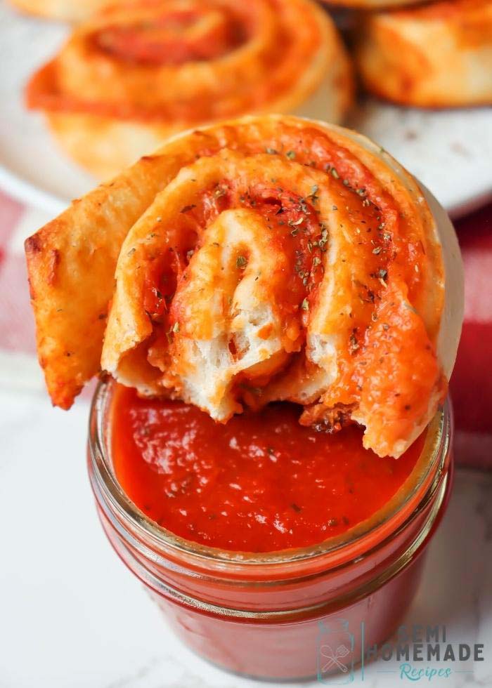 Bite Missing from Pizza Roll sitting on top of a bowl of pizza sauce