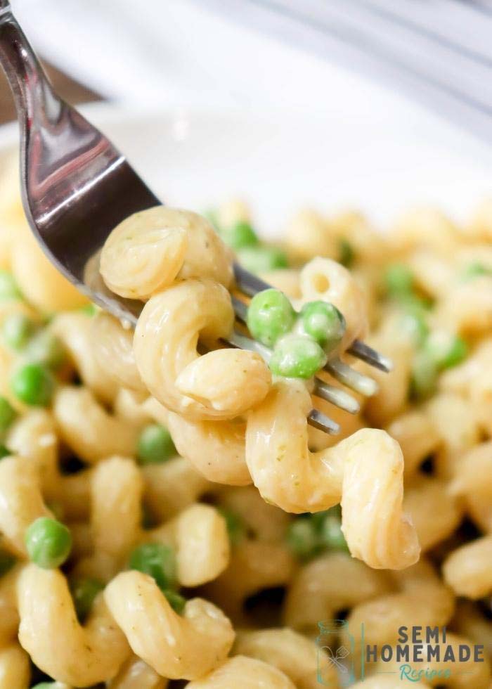 A bite of pasta on and peas on a fork