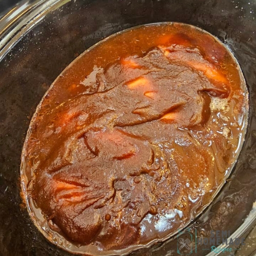 Cooked BBQ Sauce and Apple Butter poured over chicken in crock pot