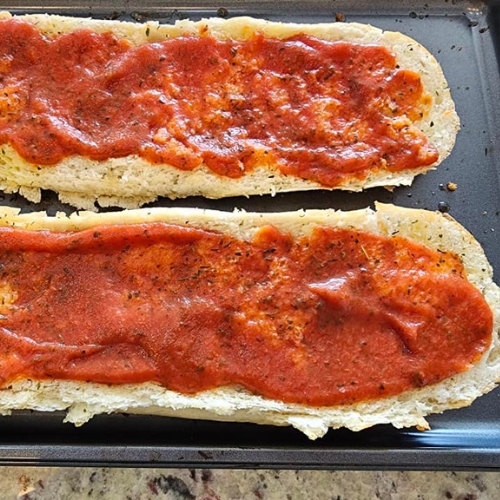 pizza sauce on bread for base of French Bread Margarita Pizza