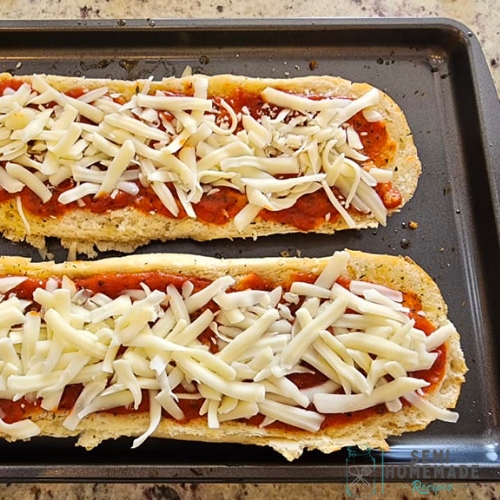 shredded cheese and pizza sauce on bread for base of French Bread Margarita Pizza