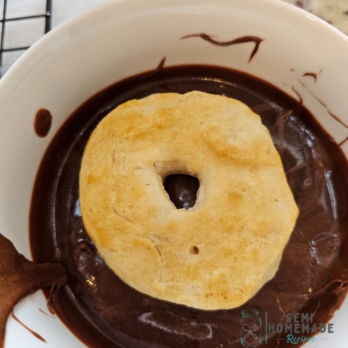 dipping donut in chocolate frosting