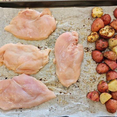 raw chicken and potatoes on sheet pan