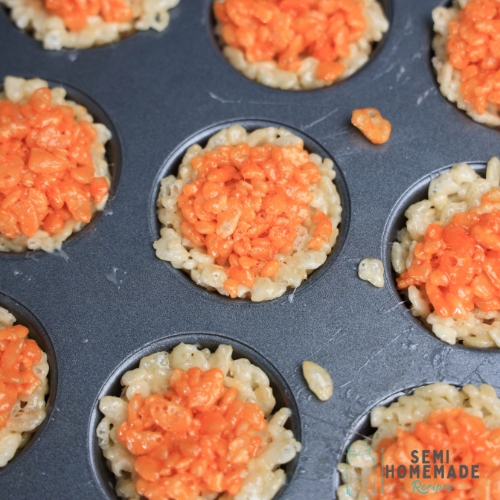 adding orange kripies to plain rice krispies in mini cupcake tin