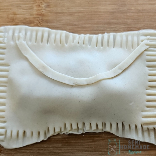 pie dough with fork crimps around edge with envelope piece